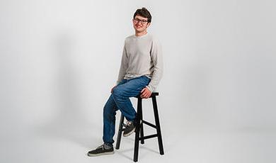 Paul Ridikas poses for a photo while sitting on a stool.